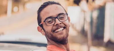 Client souriant accoudé à sa voiture